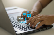 Close-up hands typing on keyboard laptop computer with chat box icons